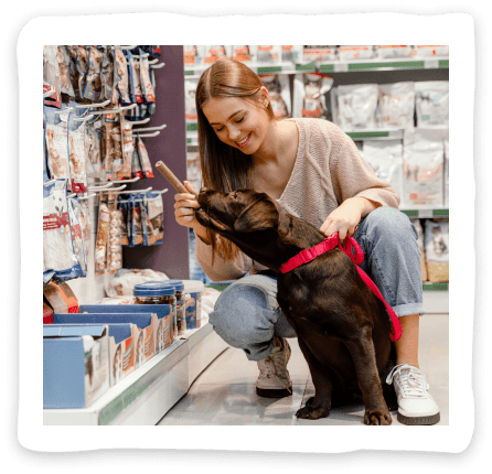 girl gives dog to smell dog treat in pet shop