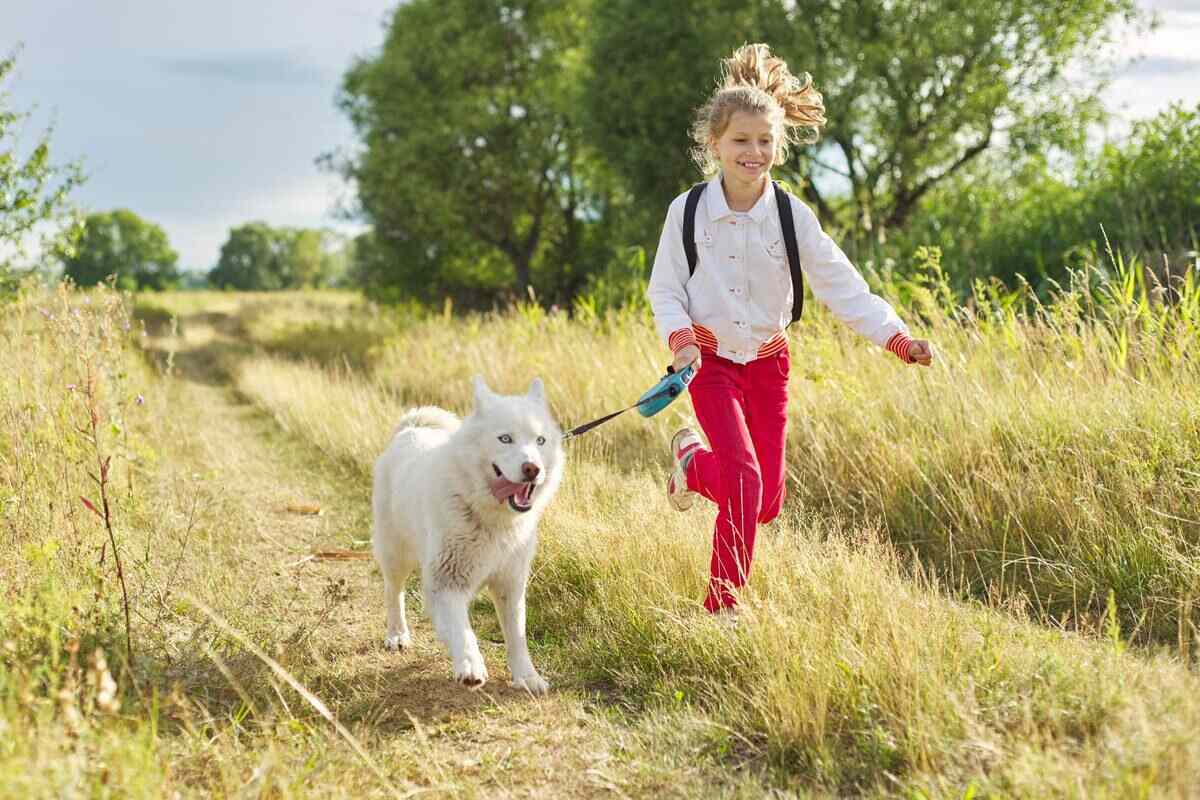 little girl running with white dog