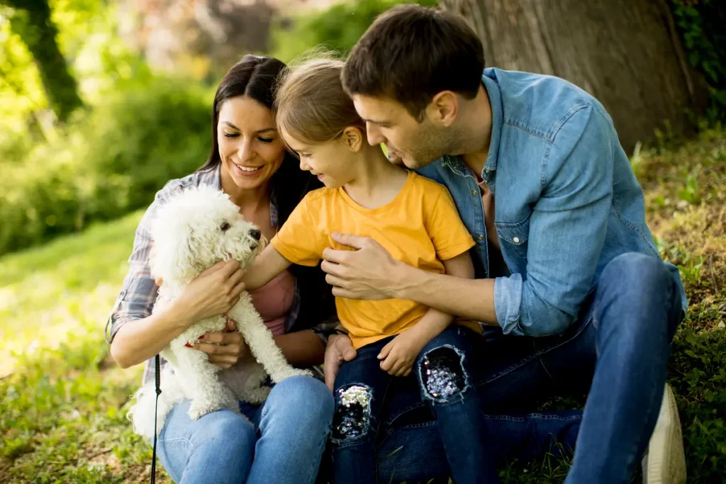 happy family with cute bichon dog in the park