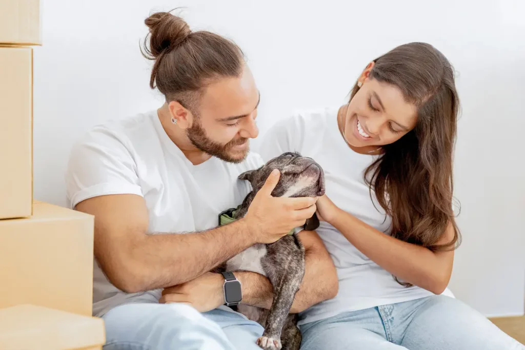 young smiling couple stroking their dog in the house